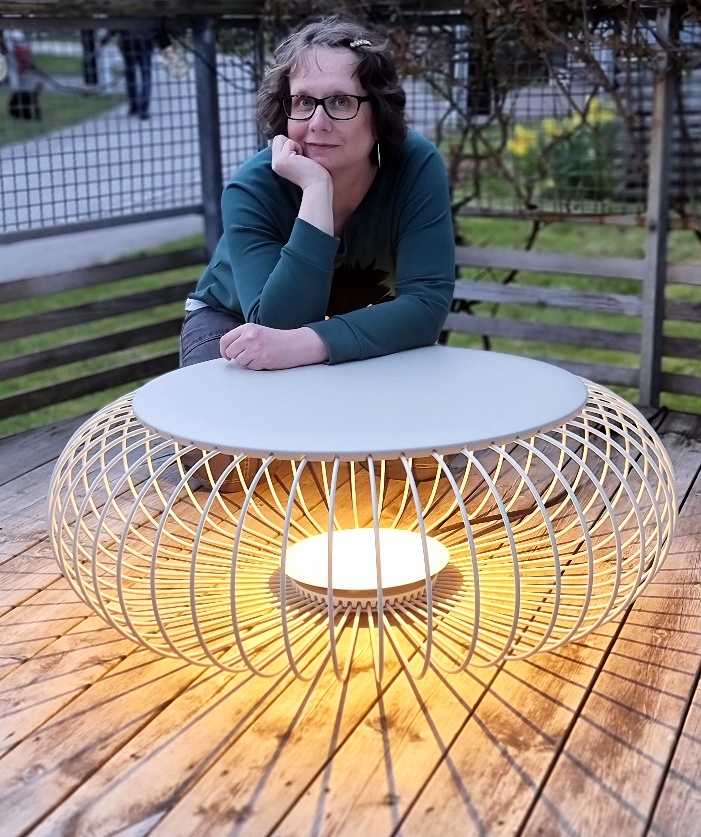 Ljusdesigner Kristina Karlberg vid en stor lampa